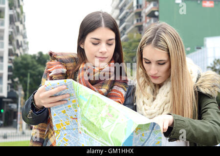Portrait of two young tourists looking at a map. Tourism concept. Outdoors. Stock Photo