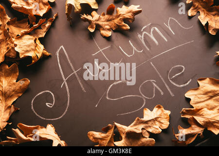 yellow leaves and the words autumn sale on a blackboard vintage style. Stock Photo