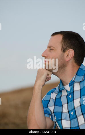 Portrait of a man looking out with his chin resting on his fist wearing a plaid shirt. Stock Photo