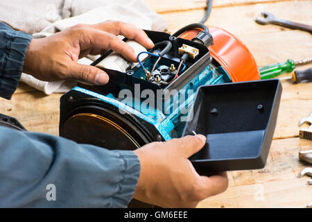 Electric motor  and man working equipment repair on wooden floor background.Background mechanic or equipment.Zoom in Stock Photo