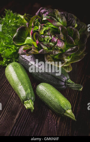 Fresh zucchini with red oakleaf lettuce on wooden table Stock Photo