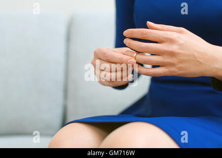 Divorce concept. Woman taking off wedding ring. Stock Photo