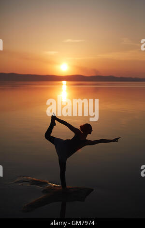 Woman relaxing by practicing yoga near the sea Stock Photo