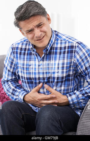 Mature Man Suffering From Stomach Pain At Home Stock Photo