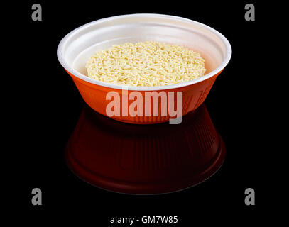Instant noodles in red plastic plate isolated on black reflecting background Stock Photo