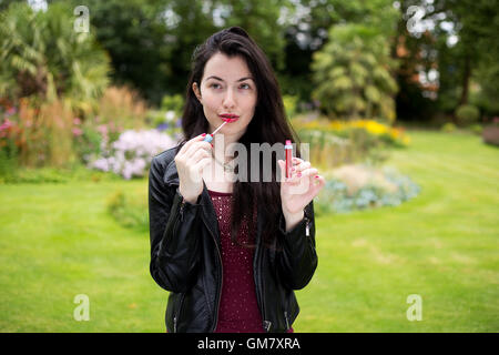 young woman putting on her lip gloss Stock Photo