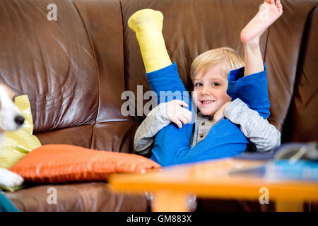 Boy with broken leg in cast sitting on couch. Stock Photo