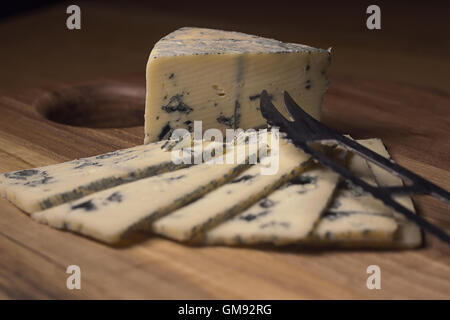 Blue cheese close up on an old wooden board and a knife Stock Photo