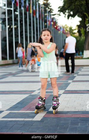 Little pretty girl on roller skates at a park Stock Photo