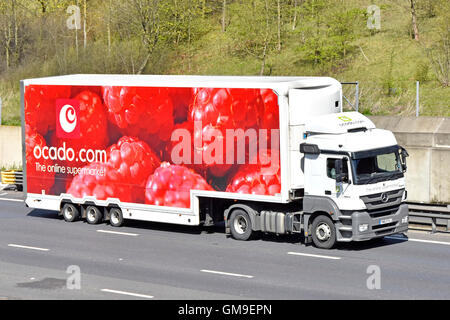 Supply chain logistics by Ocado online supermarket store delivery lorry with trailer promoting raspberry fruit driving along UK motorway in Essex Stock Photo