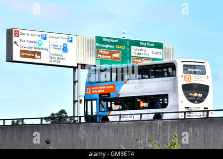 Double decker local bus operated by National Express on elevated Coventry ring road West Midlands England UK passing under overhead gantry route signs Stock Photo