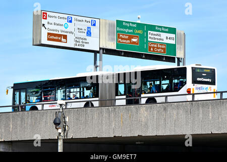 Bendy bus local route operated by National Express on elevated Coventry ring road West Midlands England UK passing under overhead gantry route signs Stock Photo