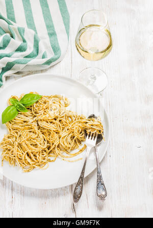 Pasta spaghetti with pesto sauce, basil, glass of white wine Stock Photo