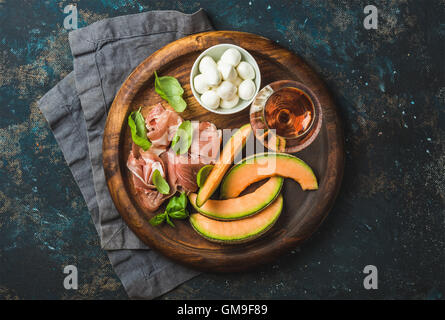 Prosciutto, cantaloupe melon, mozzarella cheese and glass of rose Stock Photo