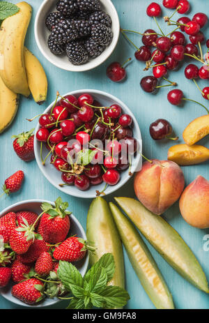 Healthy summer fruit variety on blue wooden backdrop