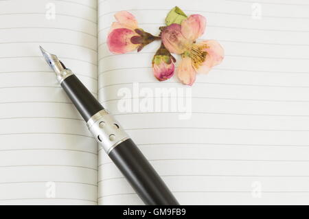 Fountain pen on a open notebook with spring flowers Stock Photo