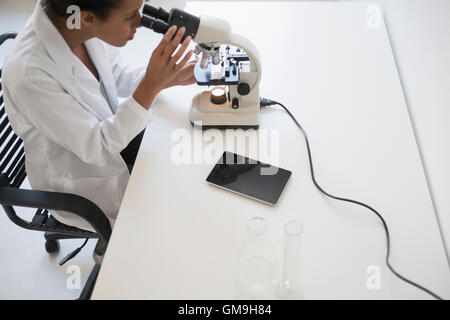 Woman scientist looking through microscope Stock Photo