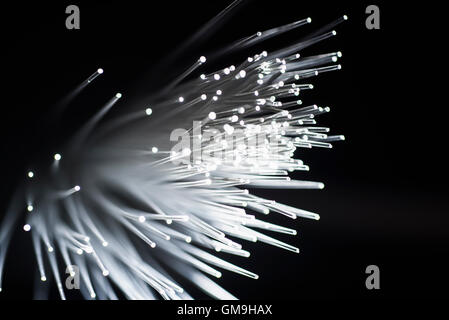 Bunch of glowing fiber optic cables on black background Stock Photo