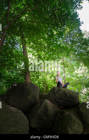 Young woman meditating on rocks in woodland Stock Photo