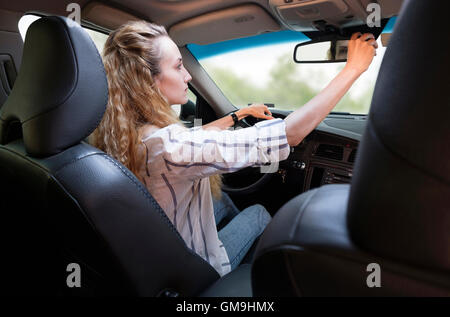 Woman adjusting rear-view mirror during driving car Stock Photo