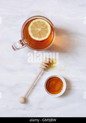 Overhead view of cup of tea with lemon and bowl of honey on marble table Stock Photo