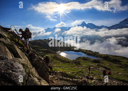 Low clouds and mist around Lac De Cheserys while hikers climb on the rocks Chamonix Haute Savoie France Europe Stock Photo