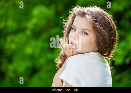 Blow kiss, young caucasian female haired model on the background of summer park Stock Photo