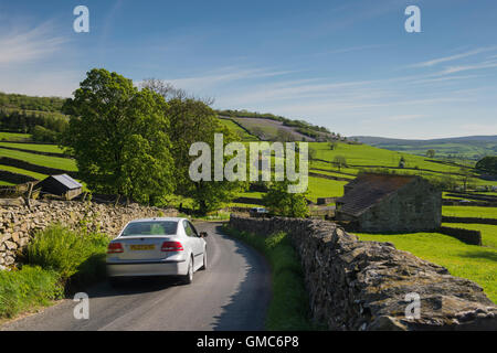 Blue sky over car driving along a narrow country lane in beautiful, scenic Crummackdale in the Yorkshire Dales, England. Stock Photo