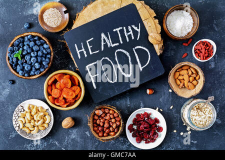 Super food selection. Various super foods and healthy foods in bowls and jars on black slate background, top view. Toned image Stock Photo