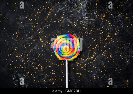 Rainbow lollipop candy on dark background. Table top view food photography Stock Photo