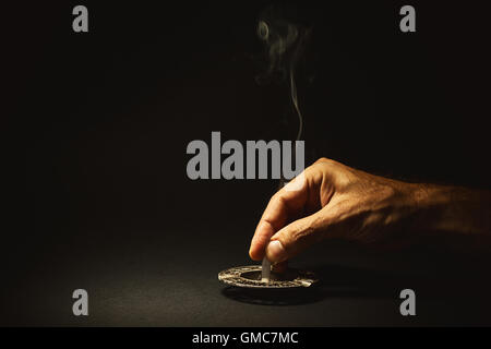 Conceptual composition about quit smoking, man's hand extinguishes a cigar. Stock Photo