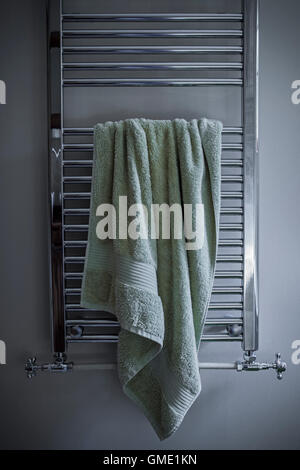 Bath towel hanging untidily on a heated towel rail. Stock Photo