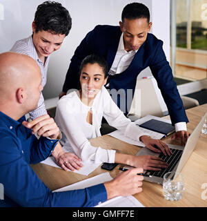 Group of four executives working together to brainstorm promotional ideas Stock Photo