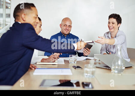 businesswoman smiling while passing a notebook to businessman during meeting Stock Photo