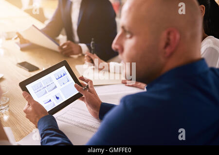 tablet in a business meeting with graphs on the screen Stock Photo