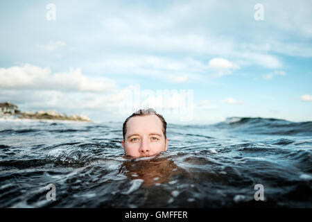 Portrait of young man in water with half of his face showing. Stock Photo