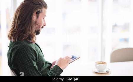 Man using tablet in cafe while seated next to window Stock Photo