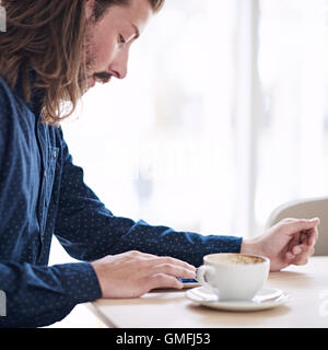 Trendy male hipster busy using his tablet on the table Stock Photo