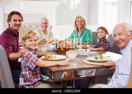 Extended Family Group Sit Around Table Eating Meal At Home Stock Photo