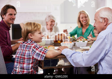 Extended Family Group Sit Around Table Eating Meal At Home Stock Photo