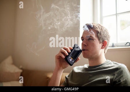 Young Man Using Vapourizer As Smoking Alternative Stock Photo