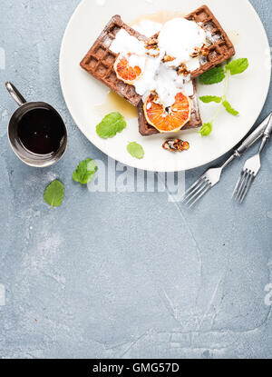 Belgian soft waffles with blood orange, cream, marple syrup and mint on white plates Stock Photo