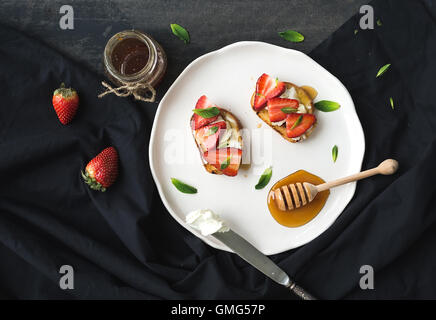 French toasts with strawberry, cream cheese, honey and mint on light ceramic plate Stock Photo