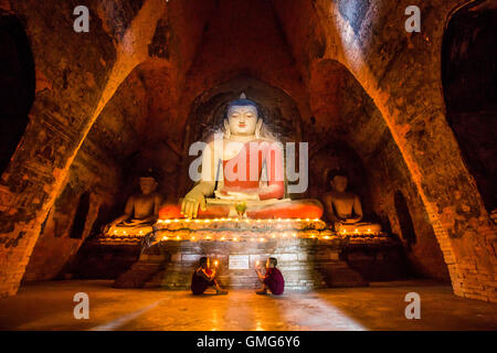 Bagan, Myanmar, November 13th, 2014: Young monks praying in front of a statue of Buddha Stock Photo