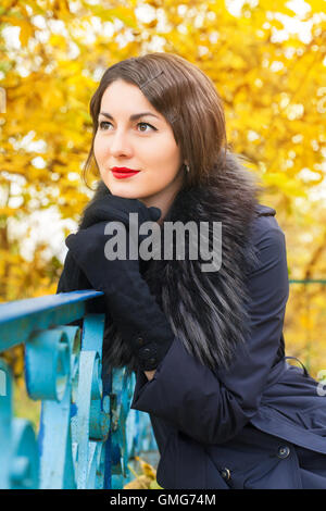 Portrait of a beautiful young woman in a black coat on a background of yellow autumn tree Stock Photo