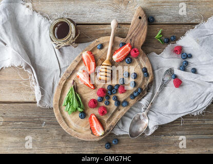 Blueberries, raspberries, strawberries, honey and fresh mint Stock Photo