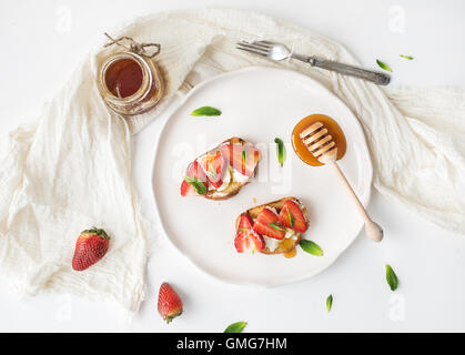 French toasts with strawberry, cream cheese, honey and mint on light ceramic plate Stock Photo