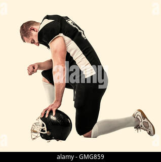 American football player, knelt on one knee, head bowed. Toned photo. Stock Photo