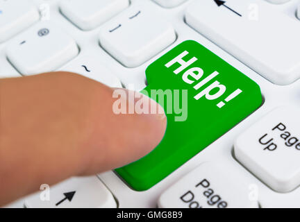 Finger pressing a Help button on a computer keyboard. Stock Photo