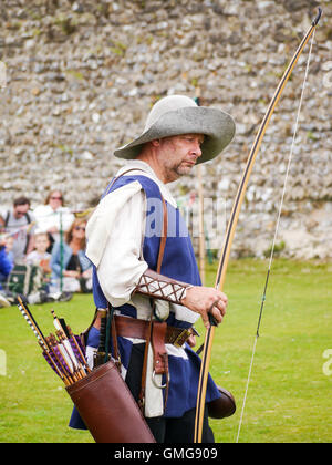 A medieval reenactor displays longbow archery techniques  within the grounds of Portchester castle, England Stock Photo